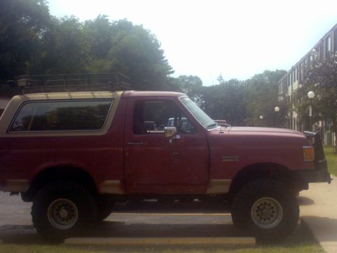1989 Ford Bronco - This red Ford Bronco, seen from the side, has a tan removable top and a roof rack.