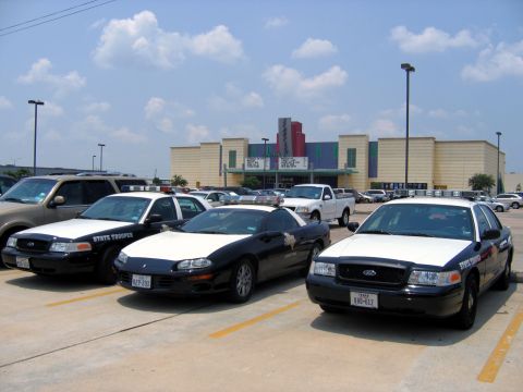 2000 Ford Crown Victoria - Several police vehicles and a sports car are parked in a lot on a sunny day.