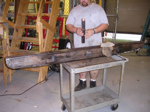 1996 Ford Bronco - A man stands in a workshop holding a custom metal bumper that is resting on a cart.