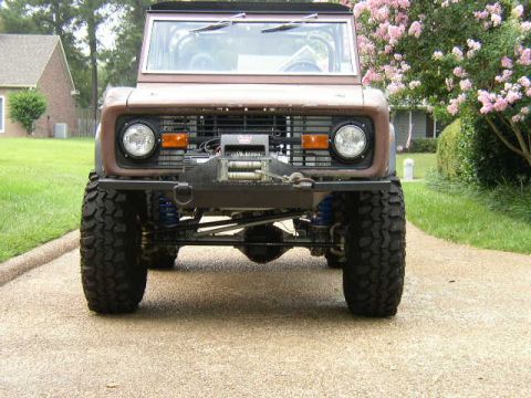 1995 Ford Bronco - A brown 1995 Ford Bronco is shown from the front, equipped with off-road tires and a winch.