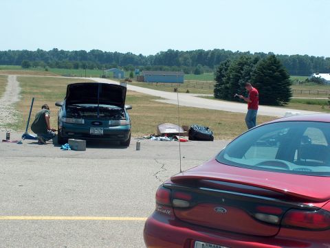 1998 Ford Taurus - Two Ford Tauruses are present, one with its hood open as a person works on it.