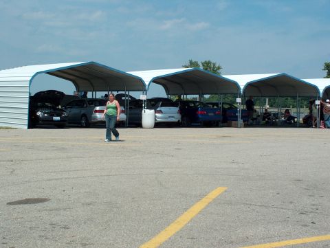1998 Ford Taurus - Several vehicles are parked under open-sided canopies on a sunny day.