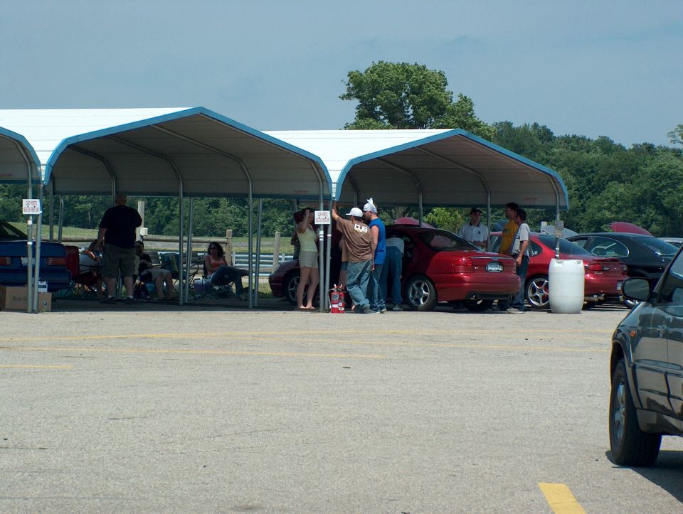 Red sedan parked under a canopy, side view