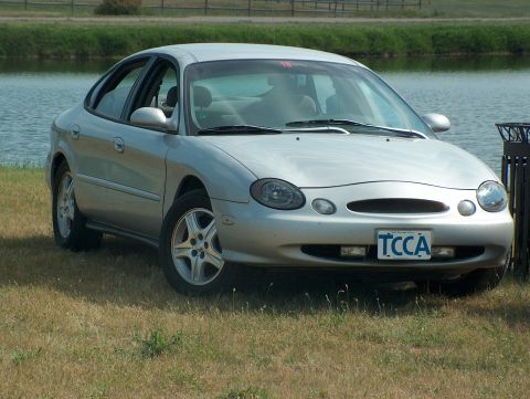 1998 Ford Taurus - Silver 1998 Ford Taurus parked near a body of water on a grassy area.