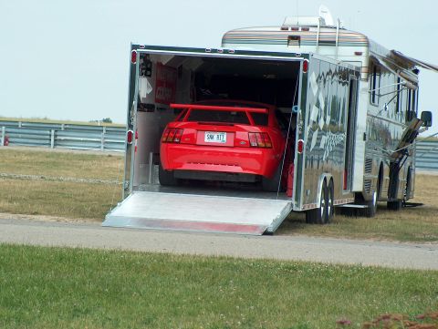 1998 Ford Taurus - A red 2000 Ford Mustang Cobra R with a prominent rear spoiler is being loaded into a trailer.