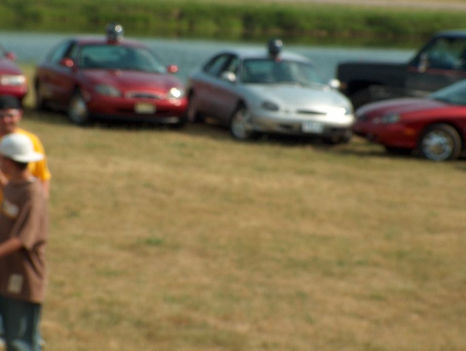 Red 1998 Ford Taurus sedan, front 3/4 view, parked on grass