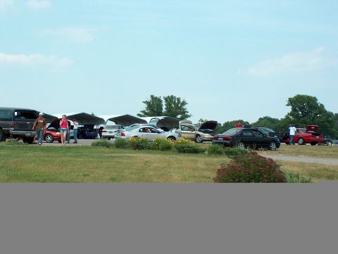 1998 Ford Taurus - A variety of vehicles are gathered outdoors, some with hoods open, under tents and in a grassy field.