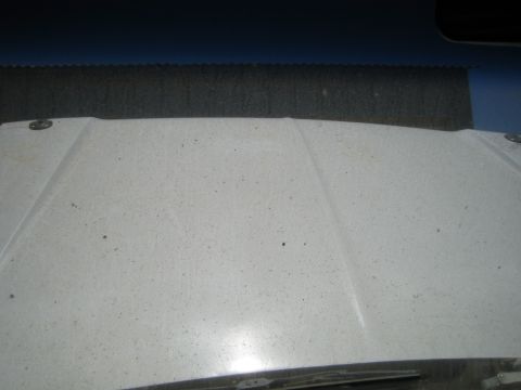 1990 Ford Bronco - close view of a dusty creased white painted panel meeting a corrugated black edge against a blue background.