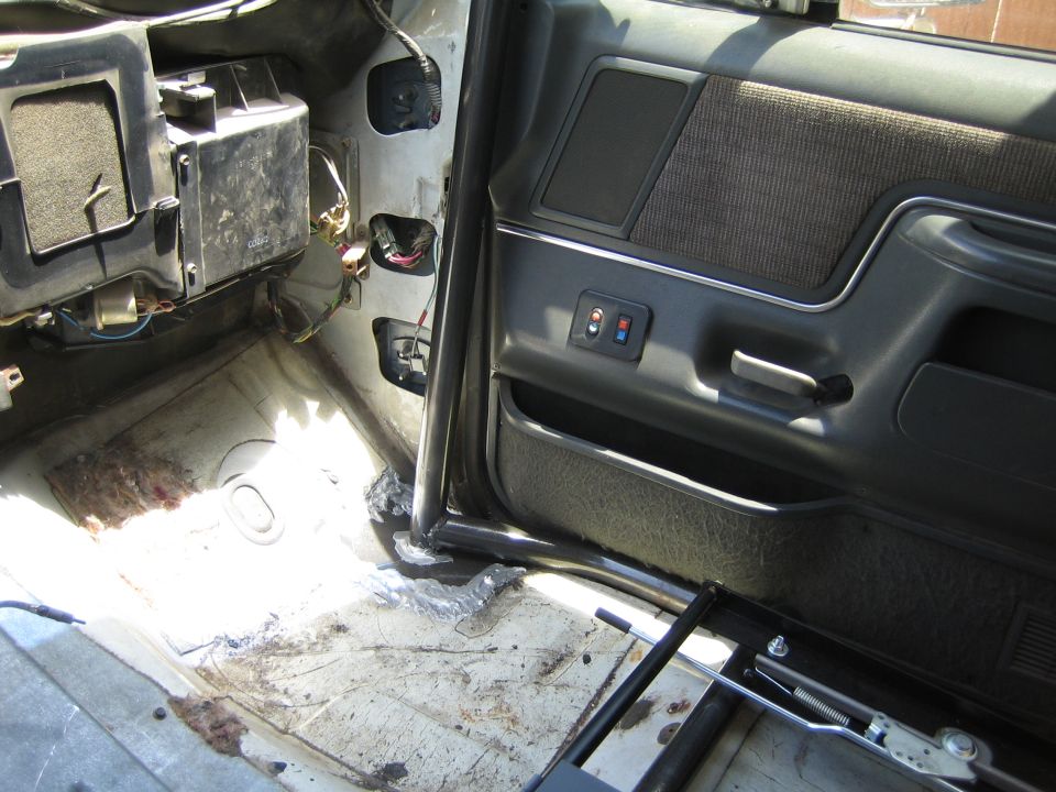 Stripped vehicle interior showing exposed floor, door panel and roll bar tube