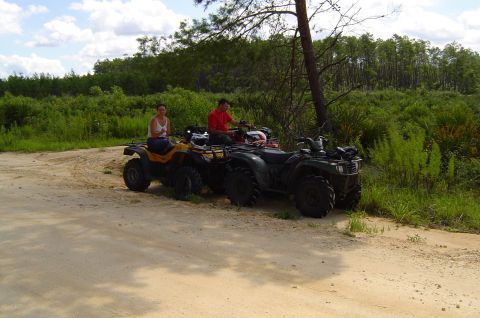 2003 Ford F-350 - Two ATVs with riders on a dirt road in a wooded area.