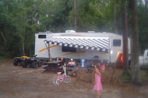 2003 Ford F-350 - RV and ATVs set up at a campsite with people relaxing and children playing.