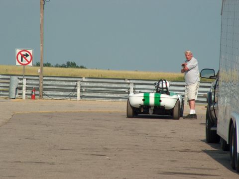 1998 Ford Taurus - A man stands next to a small white and green race car on a paved surface with a trailer nearby.
