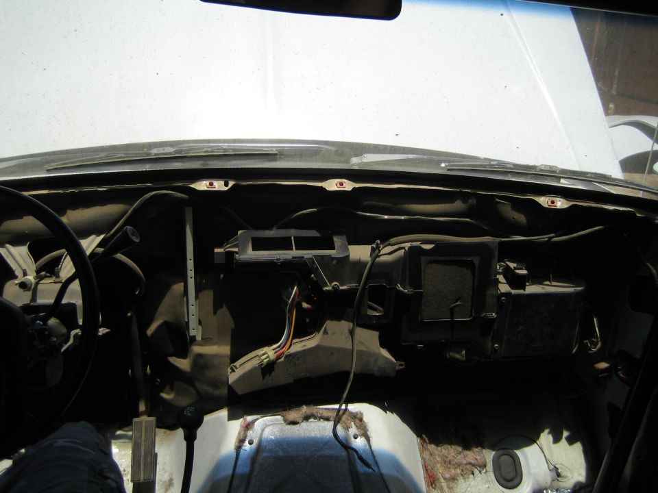 Gutted dashboard area of a vehicle with HVAC box exposed under the windshield