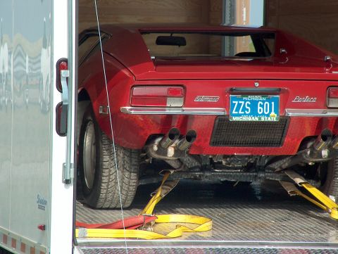 1998 Ford Taurus - A red sports car with prominent quad exhaust pipes is secured with yellow straps inside a trailer.