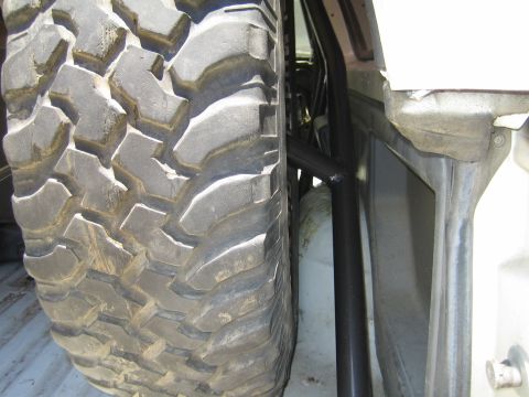 1990 Ford Bronco - close-up of an aggressive mud-terrain tire alongside a black tube and the painted inner body panel of a vehicle.