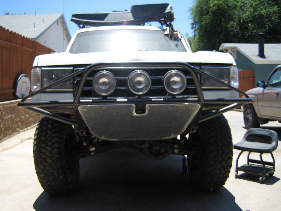 Head-on view of a white lifted SUV with prerunner bumper and three lights