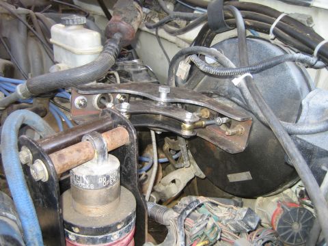 1990 Ford Bronco - Detail of an engine bay with brake master cylinder reservoir, vacuum booster, blue spark plug wires and a fabricated stainless bracket bolt…
