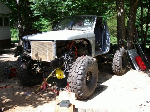 1985 Ford Bronco - This heavily modified truck is undergoing construction with its front end disassembled and large off-road tires installed.