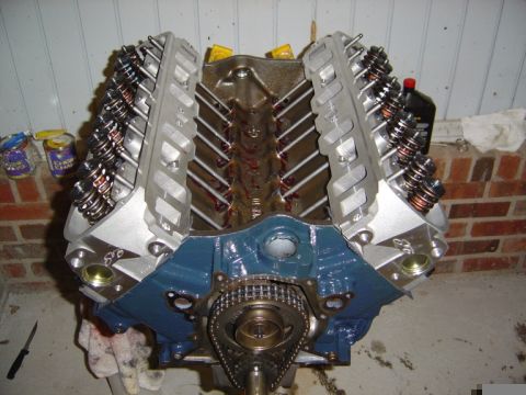 1986 Ford Bronco - Engine assembly with blue block, silver valve covers, and visible timing chain mechanism.
