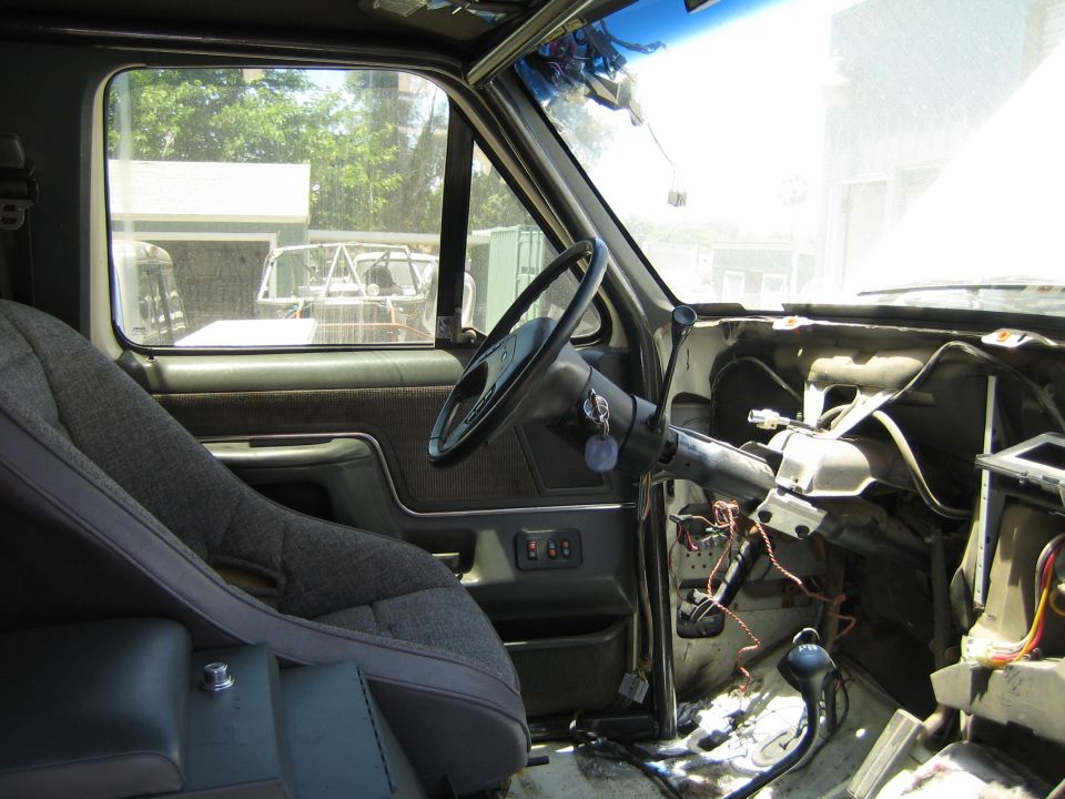 Truck interior with steering wheel and dash partially removed exposing wiring and steering column