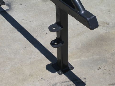 1990 Ford Bronco - Close detail of a black powder-coated tubular steel post with welded semicircular mounting tabs and a base plate bolted to a concrete floor.