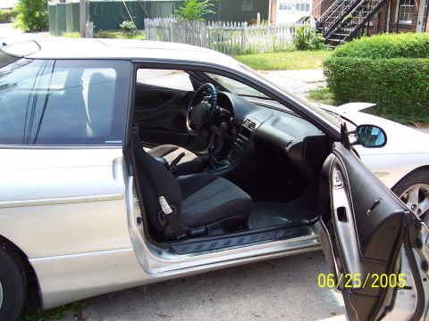 1993 Ford Probe - Interior view of a silver coupe, showing the driver's seat and dashboard. A second vehicle is partially visible in the background.
