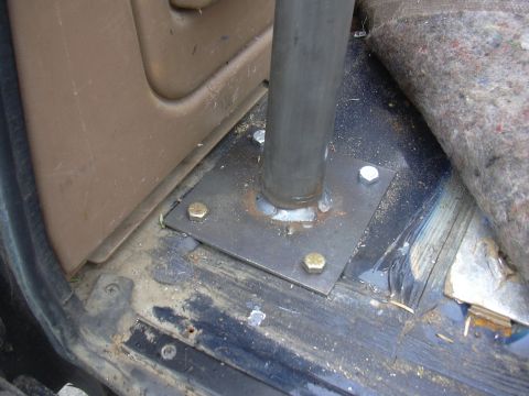 1991 Ford Bronco - Interior detail of a roll bar leg welded to a square steel foot plate and bolted through the cab floor with four hex bolts, shot next to a…