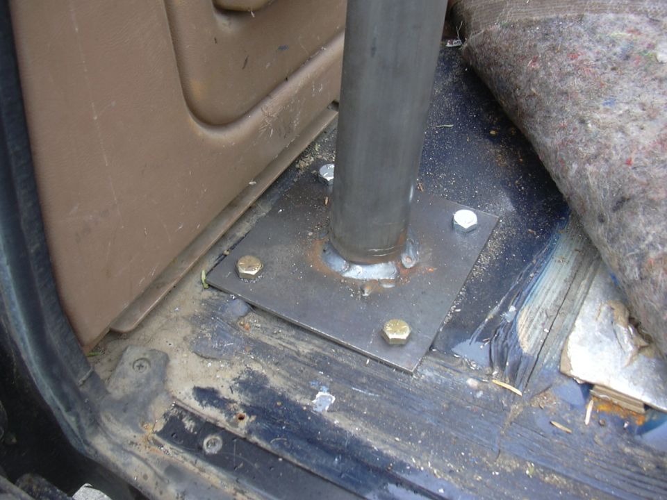 Roll bar tube welded to a bolted steel floor plate inside a truck cab