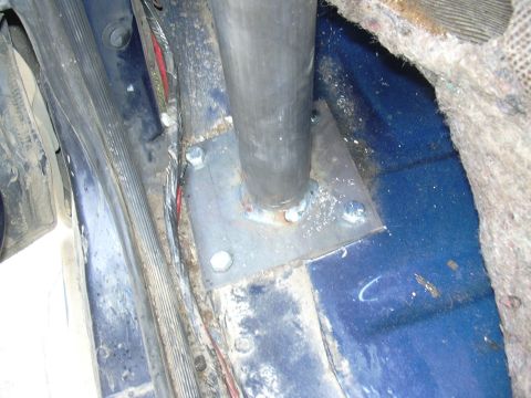 1991 Ford Bronco - Close-up of a vertical steel tube (likely a mount or pole) welded to a square steel mounting plate bolted through a blue carpeted floor. Fr…