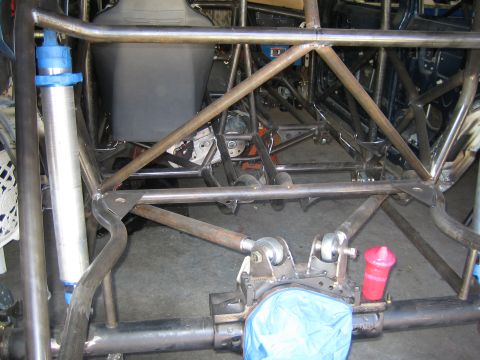 1990 Ford Bronco - Custom rear tube frame with coilover shocks, a solid axle and blue components viewed from behind in a workshop.