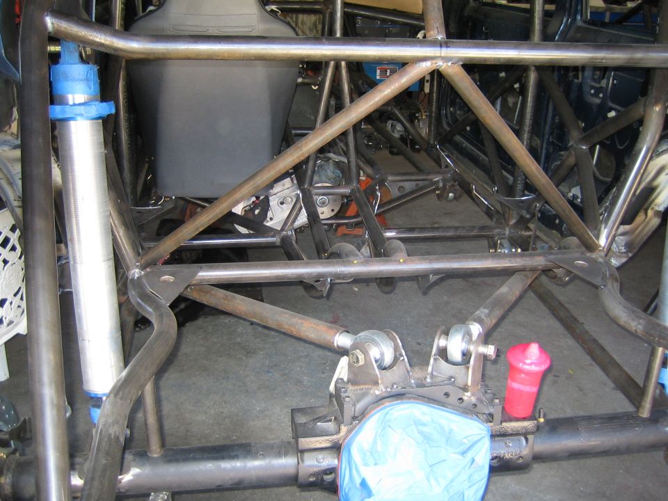 Rear tube-frame suspension and axle of a custom vehicle in a garage