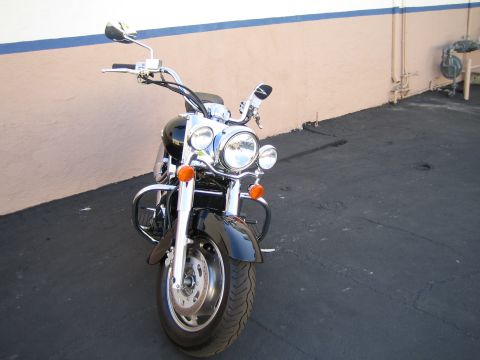 1990 Ford Bronco - Front three-quarter view of a black cruiser motorcycle with dual headlights, chrome forks and crash bars on a paved lot.