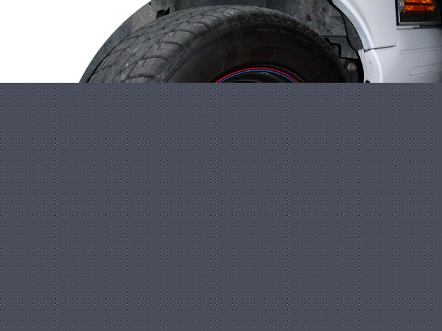 Wheel well and tire of a white vehicle, showing wear on the tire tread and a red and blue stripe on the wheel rim