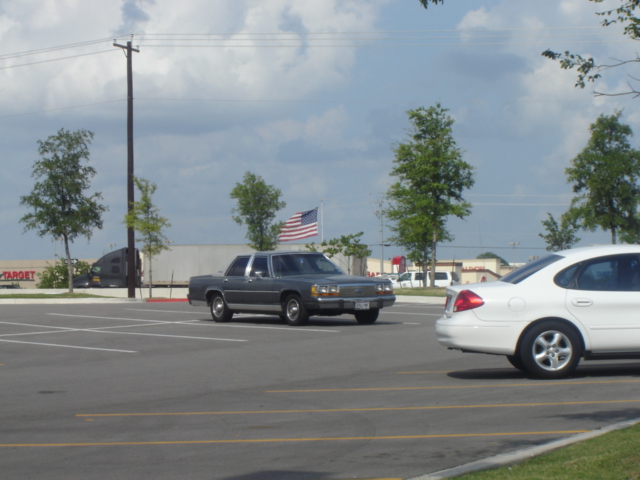 1988 Ford Crown Victoria LTD parked in a lot next to a white sedan