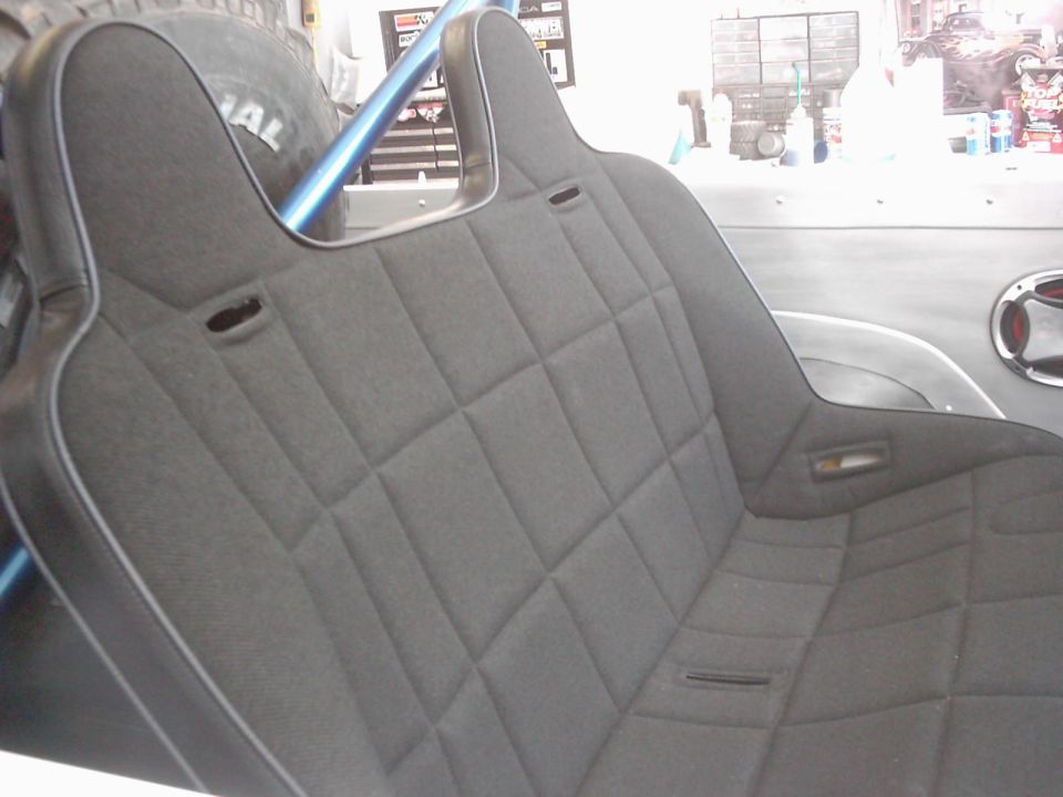 Close-up of custom diamond-stitched seats in a vehicle interior, with a spare tire visible behind the driver's side seat