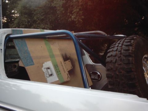 1978 Ford Bronco - A roll cage is being installed inside a vehicle, with a spare tire mounted inside.