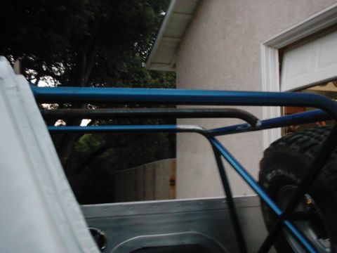 1978 Ford Bronco - Close-up view of a blue roll cage installed in a vehicle, with a spare tire visible to the right.