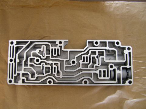 2000 Ford Excursion - This is a complex metal part with many channels, likely a valve body for an automatic transmission.
