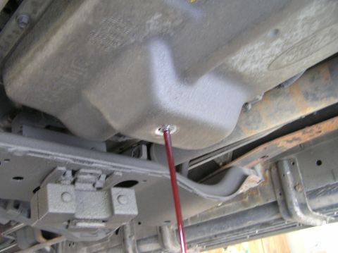 2000 Ford Excursion - Transmission fluid is being drained from the vehicle's transmission pan.