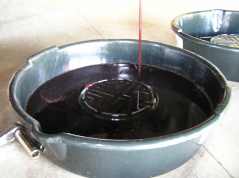 2000 Ford Excursion - Transmission fluid is being drained into a large green pan, with another pan visible in the background.