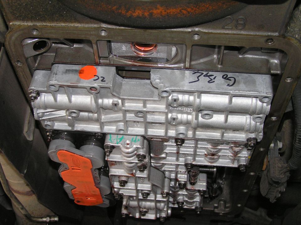 Automatic transmission valve body with orange Ford solenoid pack and hand-written marks