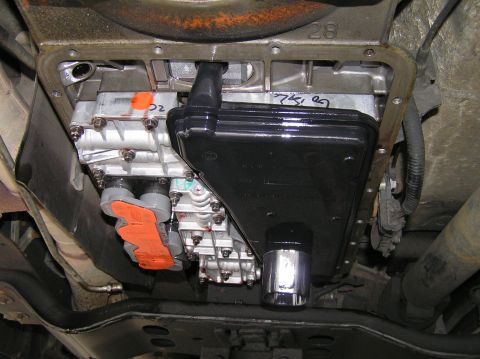 2000 Ford Excursion - Underside view of a transmission pan and filter, with orange protective covers visible on some components.
