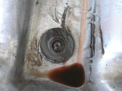 2000 Ford Excursion - Close-up view of a vehicle's valve body, showing a drain plug and accumulated fluid.