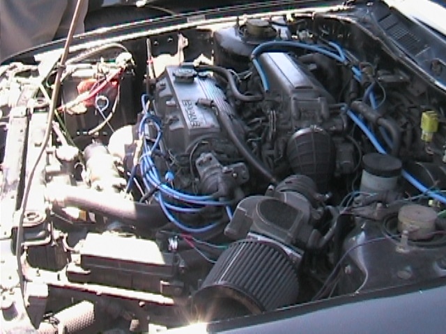 1989 Mazda MX-6 engine bay with blue spark plug wires and aftermarket air filter
