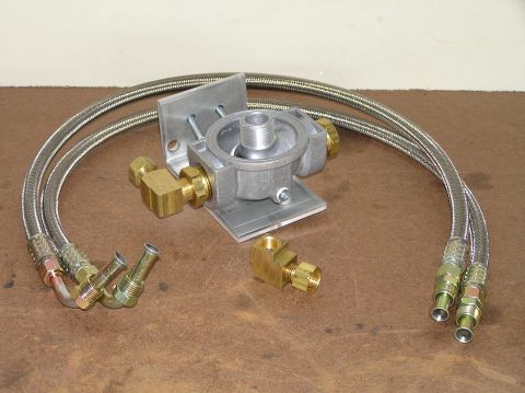 2000 Ford Excursion - A remote transmission filter kit is laid out on a brown surface, showing the main housing, braided hoses, and various brass connectors.