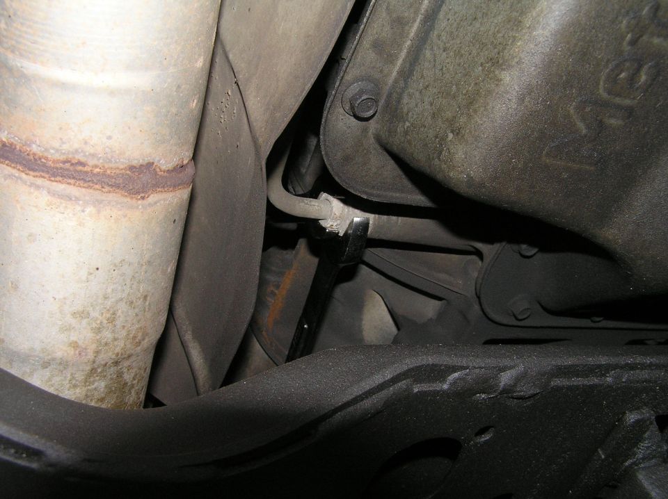 Undercarriage view with exhaust pipe, metal housing, and black chassis components