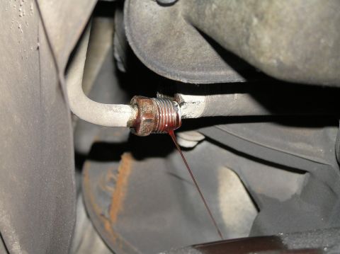 2000 Ford Excursion - A close-up shows transmission fluid leaking from a fitting on a vehicle's undercarriage.
