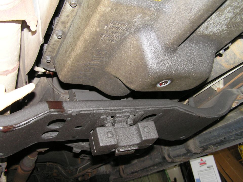 Undercarriage view of black transmission pan and crossmember with fluid drip