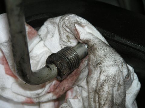 2000 Ford Excursion - A close-up view of a transmission fluid line connection being cleaned with a cloth.
