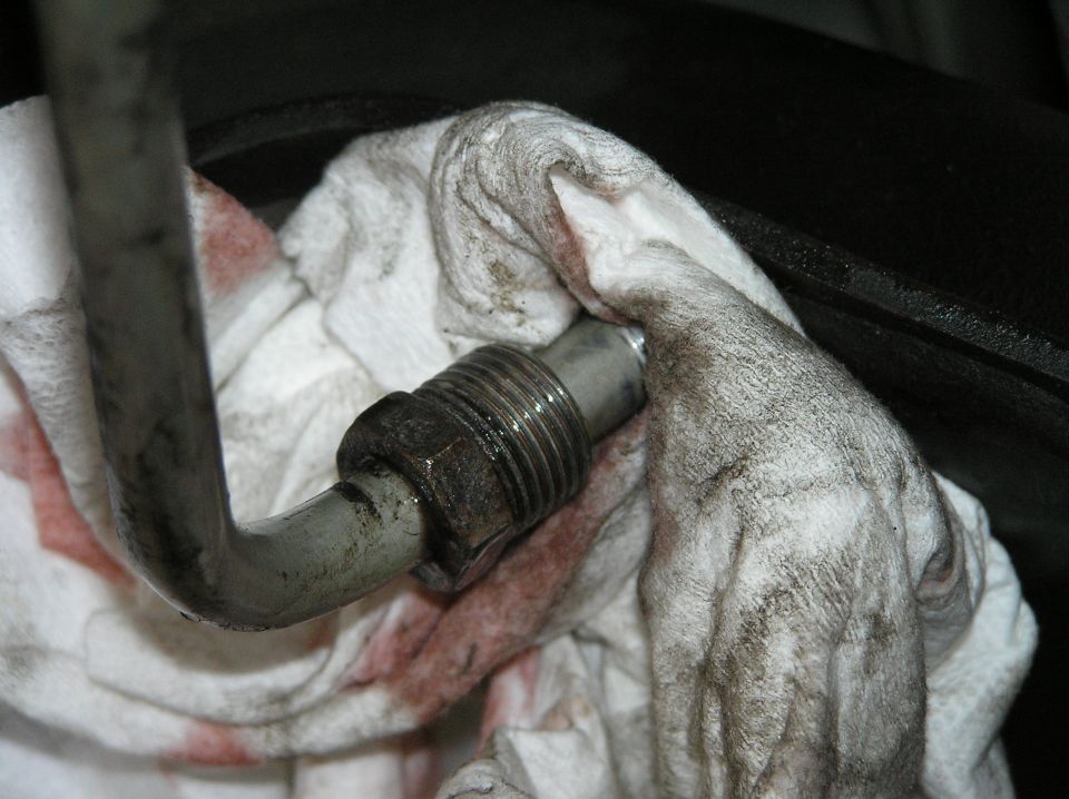 Threaded metal line fitting with hex nut wrapped in a dirty shop rag
